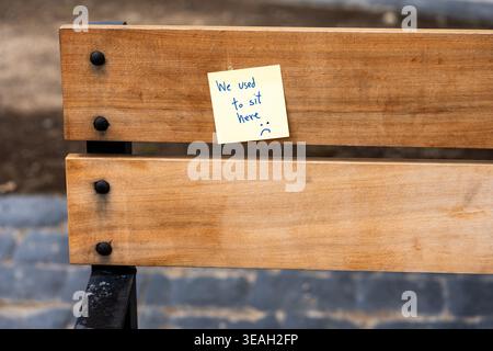 Nahaufnahme des Hinweises „Wir haben hier gesessen“ auf einer leeren Holzbank im Park, die Erinnerung symbolisiert Stockfoto