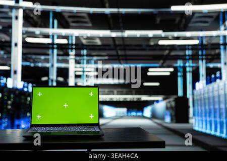 Laptop mit isoliertem Bildschirm im Rechenzentrum, der zur Konfiguration von Servereinstellungen verwendet wird. Chroma Key-Notebook in einem modernen High-Tech-Server-Hub, der für Wartungsaufgaben in der Infrastruktur verwendet wird Stockfoto