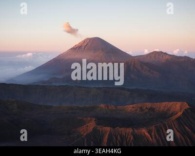 Aus der Vogelperspektive des Mount Semeru, der Rauch ausstrahlt, und des Vulkankraters des Mount Bromo bei Sonnenaufgang im Bromo Tengger Semeru Nationalpark Bromo, Ost-Java, I Stockfoto