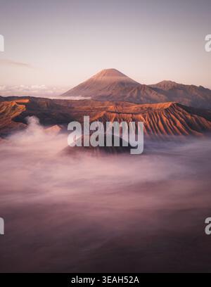 Aus der Vogelperspektive der vulkanischen Gipfel des Bromo Tengger Semeru Nationalparks, die sich während eines weichen Sonnenaufgangs über einem dicken Nebelmeer erheben Bromo, Ost-Java, Indon Stockfoto
