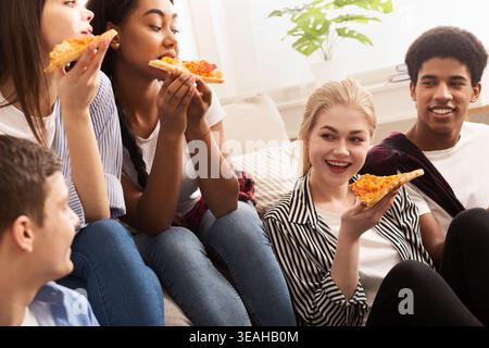 Freunde genießen gemeinsam Pizza während eines entspannten Treffens zu Hause am Nachmittag Stockfoto
