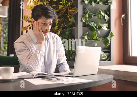Besorgt man lesen schlechte finanzielle Nachrichten online im Cafe Stockfoto