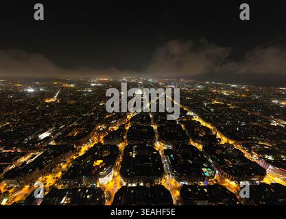 Luftaufnahme des Raster-Musters des Viertels Eixample mit beleuchteten Straßen und Stadtlichtern bei Nacht in Barcelona, Katalonien, Spanien. Stockfoto