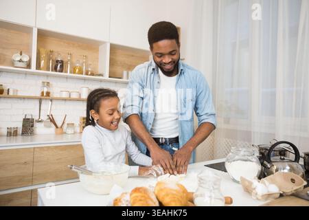 Glückliche afroamerikanische Familie Kneten Teig zusammen Stockfoto