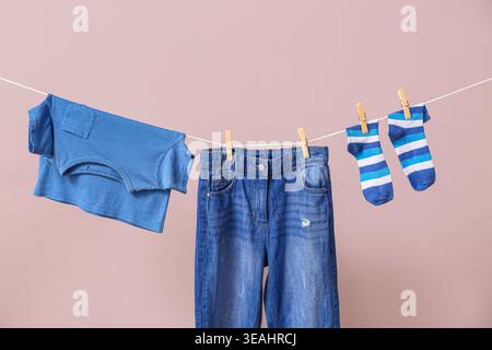 Saubere Socken, T-Shirts und Hosen, die an einem Seil an der Farbwand hängen Stockfoto