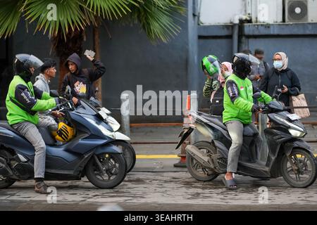 Jakarta, Indonesien - 3. Februar 2026 - Online-Fahrer in grünen Gojek-Jacken sitzen auf Motorrädern, während sie auf Bestellungen in der Nähe des Pedals warten Stockfoto