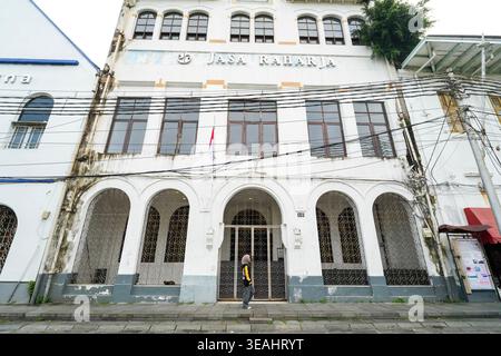 Jakarta, Indonesien - 3. Februar 2026 - Niedriger Blick auf das historische JASA Raharja-Gebäude mit niederländischer Kolonialarchitektur, weißer Fassade und Stockfoto