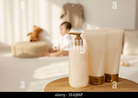 Eine Flasche Babylotion und zwei Tuben Babycreme stehen auf einem Holztisch in einem hellen, sonnendurchfluteten Kinderzimmer. Stockfoto