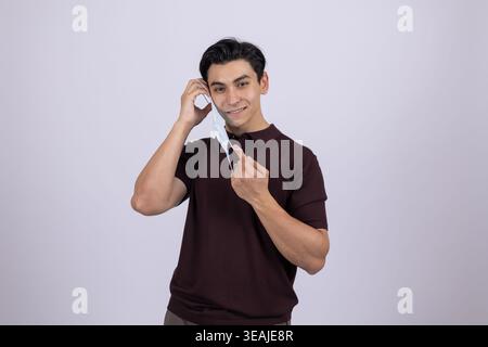 Junger Mann, der mit dem Finger auf die Kamera zeigt und lächelt Stockfoto