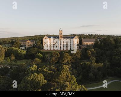 Blick aus der Vogelperspektive auf das International College of Management, Sydney, mit seiner historischen Sandsteinarchitektur und dem zentralen Turm, umgeben von üppigem grün Stockfoto