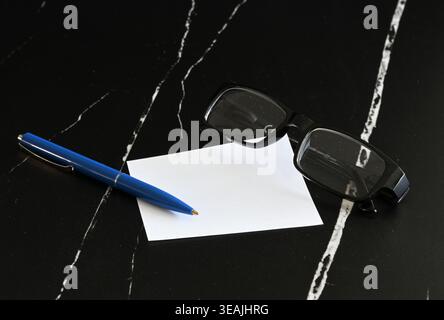 Notizblock, Kugelschreiber und Brille auf schwarzem Hintergrund Stockfoto