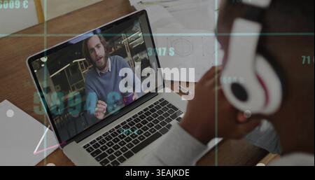 Zeigt einen offenen Laptop-Bildschirm, Mann in blauem Pullover spricht, Gesten am Schreibtisch mit Kopfhörerüberzug Stockfoto