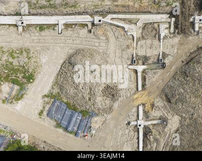 Aus der Vogelperspektive der Neustadt-Infrastruktur-Baustelle mit Betonfundamenten, Erdhügeln und Rohrbündeln in Taiwan. Stockfoto