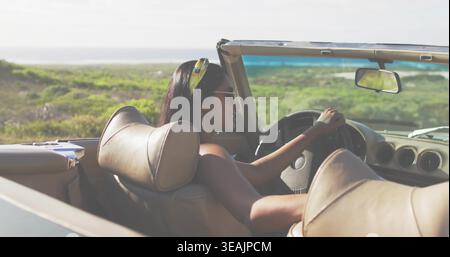 Eine Indianerin, die das Cabriolet entlang der Küstenstraße steuert, trägt Kopftuch und Sonnenbrille Stockfoto
