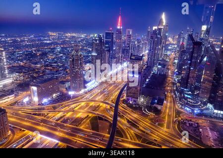 Luftaufnahme der beleuchteten Skyline von Dubai bei Nacht mit dem Verkehr der Sheikh Zayed Road und leuchtenden Wolkenkratzern unter einem tiefblauen Dämmerungshimmel Dubai, Stockfoto