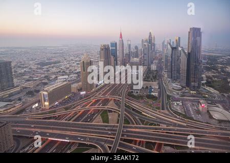 Luftaufnahme der modernen Wolkenkratzer und komplexen Autobahnkreuzungen entlang der Sheikh Zayed Road in der Abenddämmerung in Dubai, Dubai, Vereinigte Arabische Emirate. Stockfoto