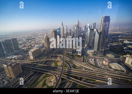 Luftaufnahme der Skyline der Sheikh Zayed Road mit modernen Wolkenkratzern und komplexen Autobahnkreuzungen unter einem klaren blauen Himmel Dubai, Dubai, Vereinigte Arabische Emirate Stockfoto
