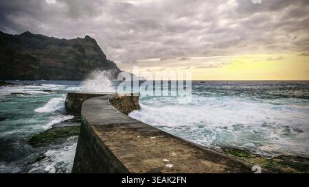 Ein Pier führt in das Meer unter dramatischen Wolken und Wellen bei Sonnenuntergang, Ponta do Sol, Santo Antao, Cabo Verde, Kap Verde, Kap Verde Stockfoto