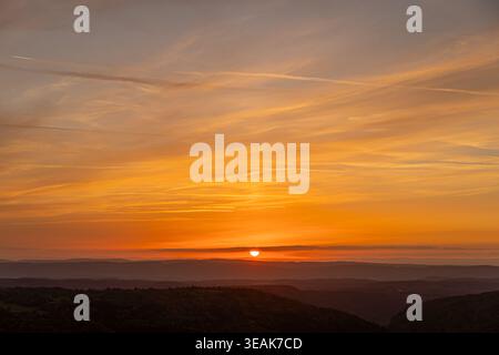 Die Farben des Sonnenuntergangs bemalen den Abendhimmel über sanften Hügeln Stockfoto