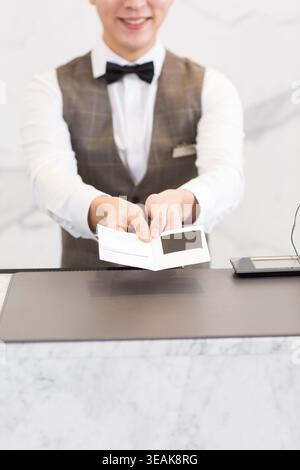 Ein Hotelrezeptionist überreicht einem Gast einen Hotelkartenschlüssel. Stockfoto