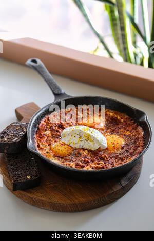Rustikale Skillet Mit Warmen Käseeiern, Begleitet Von Hausgemachter Sauce Und Pikanten Zitronenscheiben Stockfoto