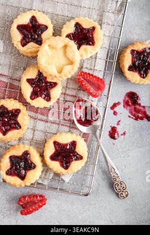 Szene Mit Frisch Gebackenen Sternförmigen Cookies, Gekühlt Auf Rack Mit Frischen Himbeeren Und Glossy Marmelade Stockfoto