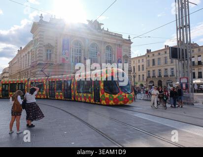 Farbenfrohe Straßenbahnlinie mit Blumenmuster, die vor dem Opernhaus am Place de la Comedie, Montpellier, Occitanie, Frankreich, vorbeiführt. Stockfoto