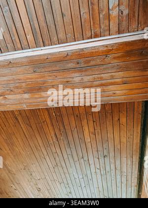 Abgewinkelter Blick auf Holzdecken und Wandpaneele mit sattem Naturmaserung. Warme Holztöne und klare Linien schaffen einen vielseitigen Hintergrund für Architektur Stockfoto