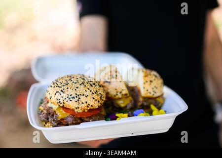 Nahaufnahme eines frisch zubereiteten Cheeseburgers mit doppelten Rindfleischpasteten, geschmolzenem Käse und Sesambrötchen auf einer Holzoberfläche, die saftig ist Stockfoto