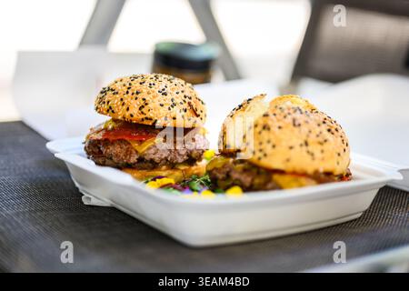 Nahaufnahme eines frisch zubereiteten Cheeseburgers mit doppelten Rindfleischpasteten, geschmolzenem Käse und Sesambrötchen auf einer Holzoberfläche, die saftig ist Stockfoto