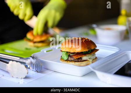 Nahaufnahme eines frisch zubereiteten Cheeseburgers mit Rindfleisch, geschmolzenem Käse und Brötchen mit saftigem Gourmet-Streetfood. Stockfoto