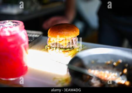 Nahaufnahme eines frisch zubereiteten Cheeseburgers mit Rindfleisch, geschmolzenem Käse und Brötchen mit saftigem Gourmet-Streetfood. Stockfoto