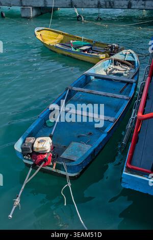 Farbenfrohe traditionelle thailändische Longtail- und Touristenboote, die in brillantem türkisfarbenem Wasser an einem tropischen Reiseziel in Thailand vor Anker gehen. Stockfoto