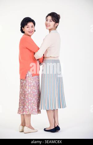 Zwei Frauen verschiedener Generationen umarmen und lächeln einander an. Stockfoto