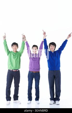 Drei junge Freunde stehen zusammen und heben die Arme zum Feiern. Stockfoto
