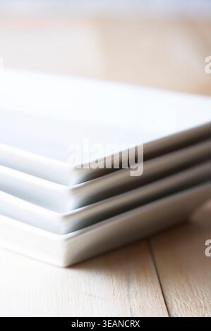 Ein Stapel sauberer, weißer Teller sitzt auf einem Holztisch. Stockfoto