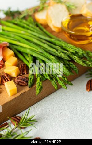 Verwöhnen Sie sich mit einer wunderschön gestalteten Wurstplatte mit lebhaftem Spargel, herzhaftem Wurstwaren, verschiedenen Käsesorten und frisch geröstetem Brot, ideal für Stockfoto