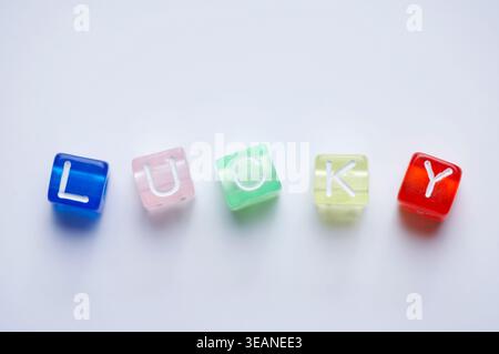 Ein einzelner, farbenfroher und transparenter Buchstabe „L“ aus dem Wort „LUCY“ ist auf einer weißen Oberfläche angeordnet. Stockfoto