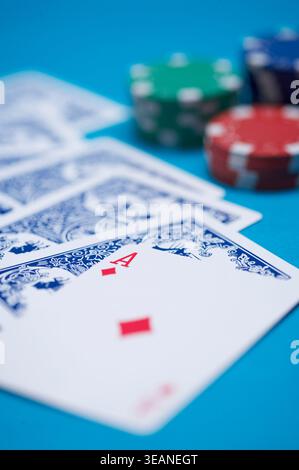 Ein Kartenspiel und Pokerchips sind auf einem blauen Tisch verteilt. Stockfoto
