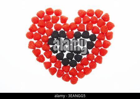 Ein herzförmiges Arrangement aus roten und schwarzen Jelly Beans auf weißem Hintergrund. Stockfoto