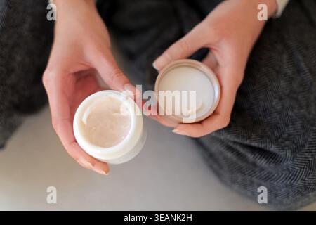 Öffnen Sie die Feuchtigkeitscreme in den Händen. Nahaufnahme der Hände, die ein offenes Glas mit Gesichtscreme halten, zeigen Hautpflegeroutine, Feuchtigkeitsspendende Produkt und persönliche Stockfoto