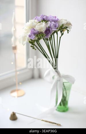 Wunderschöne Freesien-Blumen in Vase auf dem Tisch drinnen. Wunderschöne violette Freesieblume. Romantisches Stillleben im Frühling. Romantischer Hintergrund mit Blumen Stockfoto