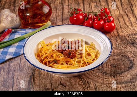 Klassische Spaghetti mit herzhaften Fleischbällchen in reichhaltiger Tomatensauce. Frische Kirschtomaten, Knoblauch, Chili, grüne Zwiebeln und eine Flasche Olivenöl machen einladende rus aus Stockfoto
