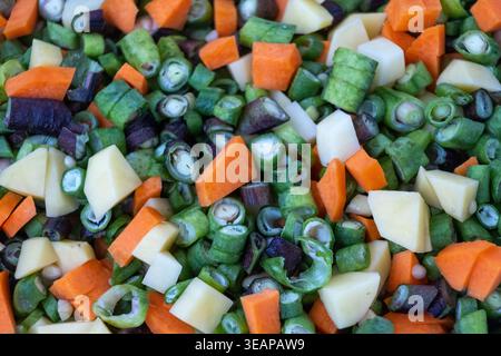 Nahaufnahme von frisch gehacktem gemischtem Gemüse: Grüne Bohnen, OrangenKarotten und zum Kochen vorbereitete Kartoffeln. Ideal für kulinarische Blogs, Stockfoto