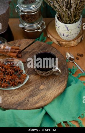 Blick von oben auf schwarzen Kaffee in Vintage Cup mit Zimtstangen, Sternanis und Lavendel auf Holzbrett. Hintergrund zum Trinken Stockfoto