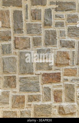 Steinmauer mit rechteckigen grauen und braunen Felsen in hellem Mörtel, vertikale Mauerwerksoberfläche mit strukturiertem Stein, Vollrahmenhintergrund, rustikales Gebäude Stockfoto
