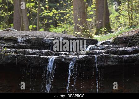 Das Wasser kaskadiert eine Reihe von Stufen hinunter in einen Springbrunnen-Wasserfall Stockfoto