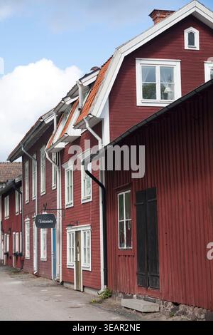 Traditionelle rote Holzhäuser in der Gruvstugetorget Straße mit dem historischen 'Veterinär' Schild, Kopparberg, Schweden. Stockfoto