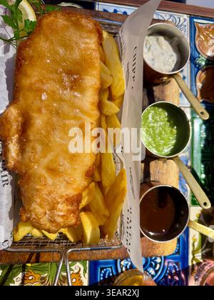 Klassisches Fish-and-Chips-Gericht, serviert mit 3 Beilagensaucen in einem Restaurant in Knightsbridge, London. Stockfoto