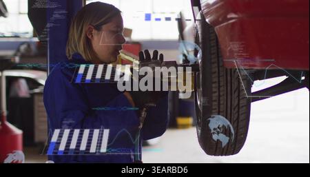 Drehmechaniker mit blauem Overall, schwarzen Handschuhen am Lift mit Schlagpistole und AR-Überzügen. Techniker, Frau, Garage, Werkstatt, Rad, Reifen, Nabe Stockfoto